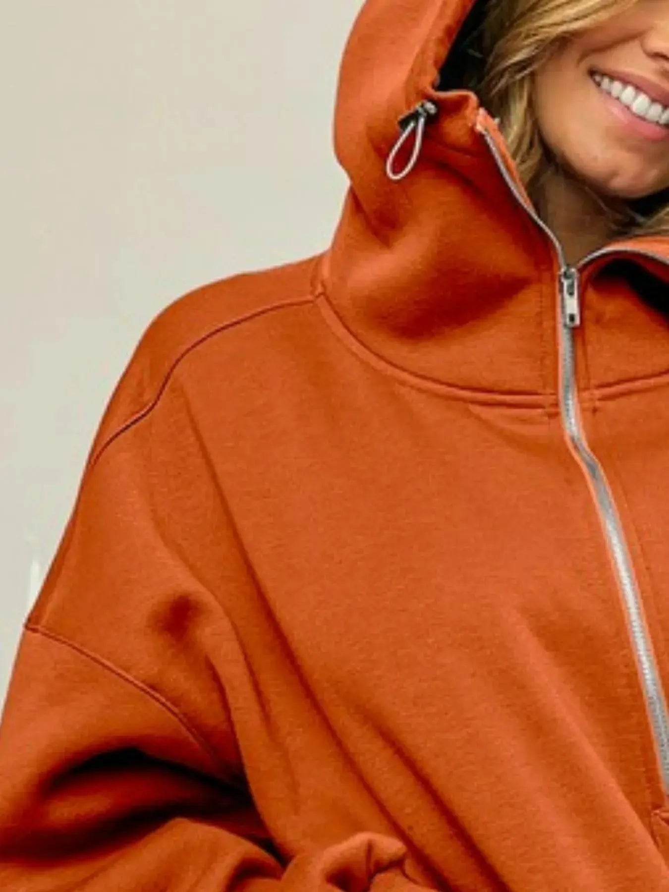 Close-up of orange BiBi oversized hoodie with zip detail.