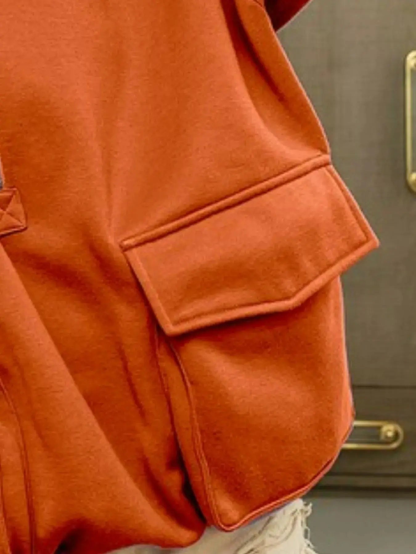 Close-up pocket view of orange BiBi oversized hoodie.