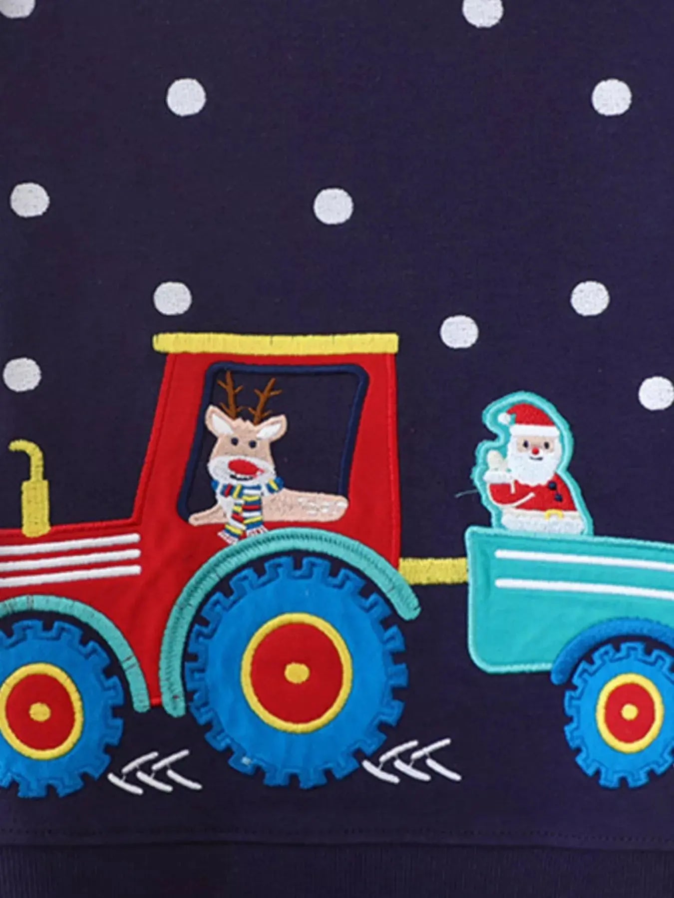 Close-up of embroidered Christmas train and snowflake details on sweatshirt.