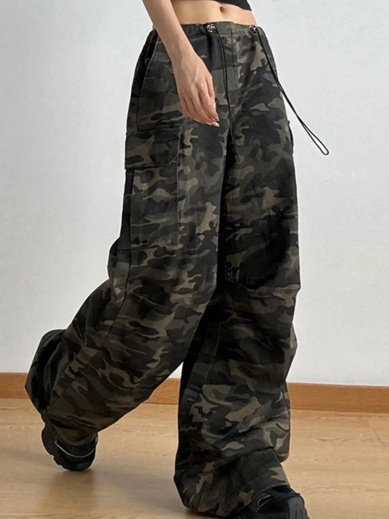 Close-up of camo print wide leg cargo jeans highlighting drawstring waist and.