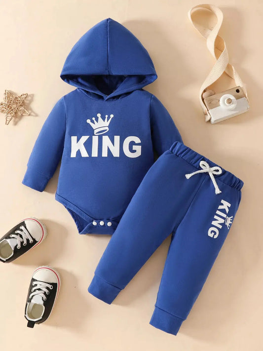 Flat lay of blue hoodie and jogger pants set for kids with KING crown print.