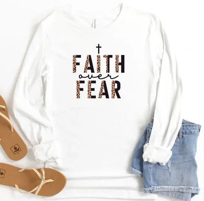 Cream long sleeve Faith Over Fear graphic tee with leopard accent design, styled with denim.