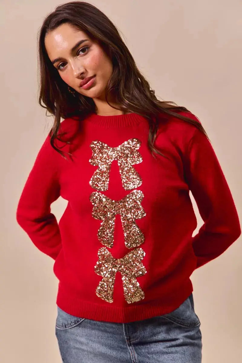 Red Christmas sweater with sequin bow ribbon detail on model.