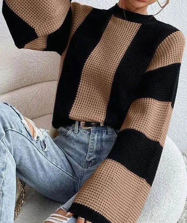 Woman wearing black and tan striped Colorblock bell sleeve knit sweater with ripped jeans.