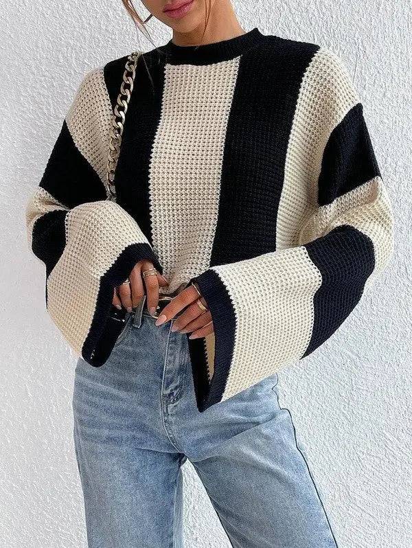 Woman wearing black-and-white striped bell sleeve knit sweater styled with jeans.