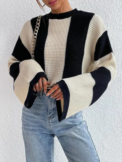 Woman wearing black-and-white striped bell sleeve knit sweater styled with jeans.