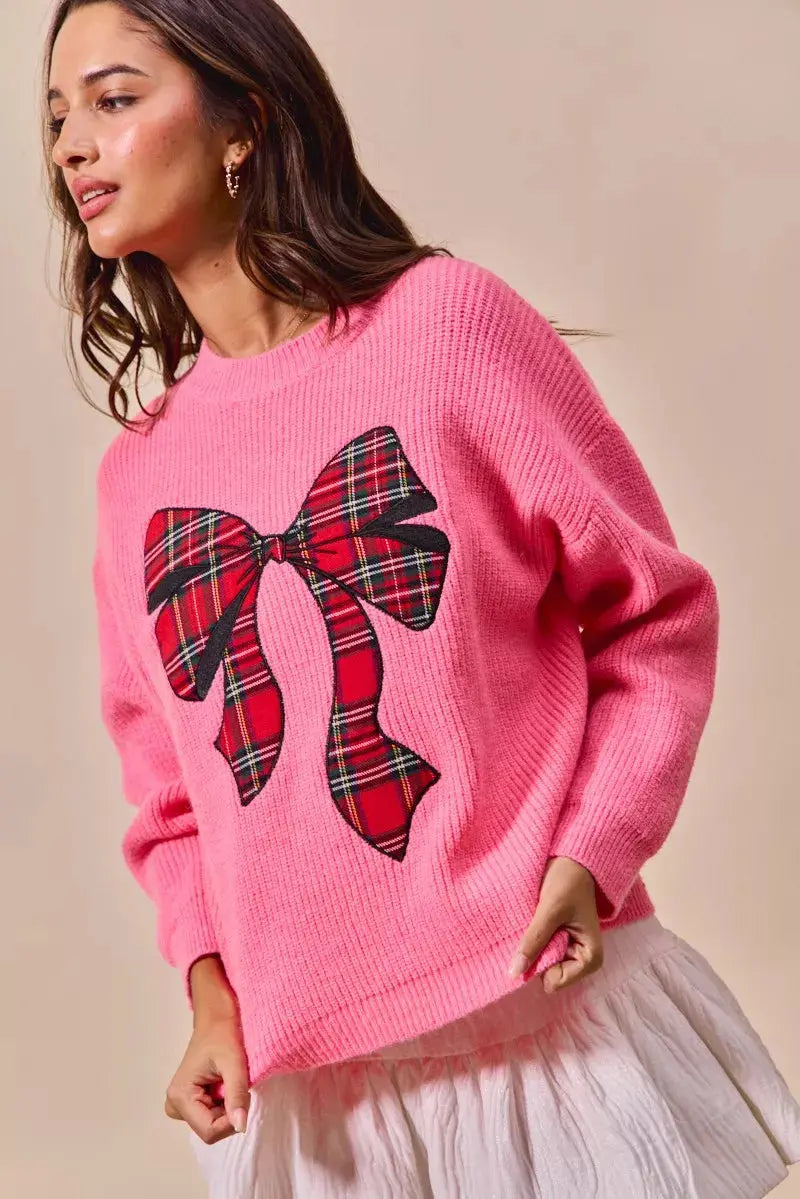 Side pose in festive pink Christmas sweater.