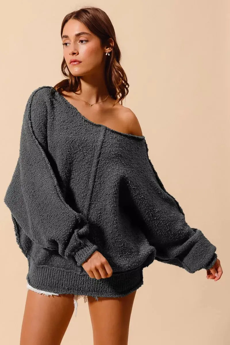 Model wearing loose fit exposed seam slouchy boucle sweater in charcoal grey — front view