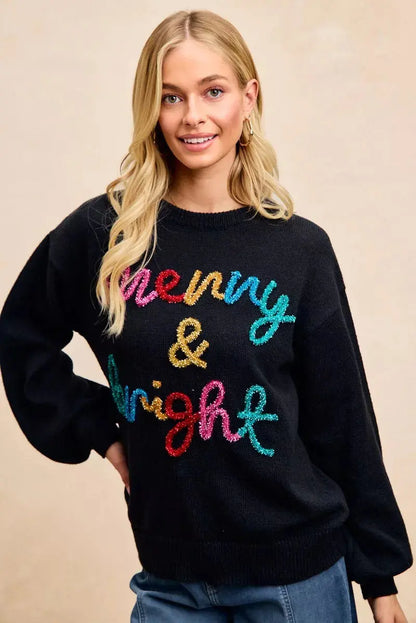 Front view of BiBi tinsel lettering holiday sweater with female model - hands on hip.