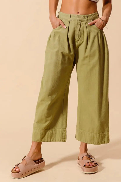 Front view of olive green wide leg chino pants with model hands in pocket