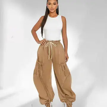 Woman wearing beige cargo pants and a white top on a light gray background