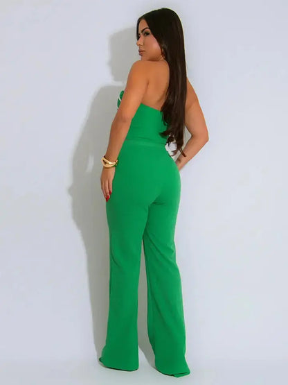 Woman wearing a green strapless jumpsuit against a white background - back view