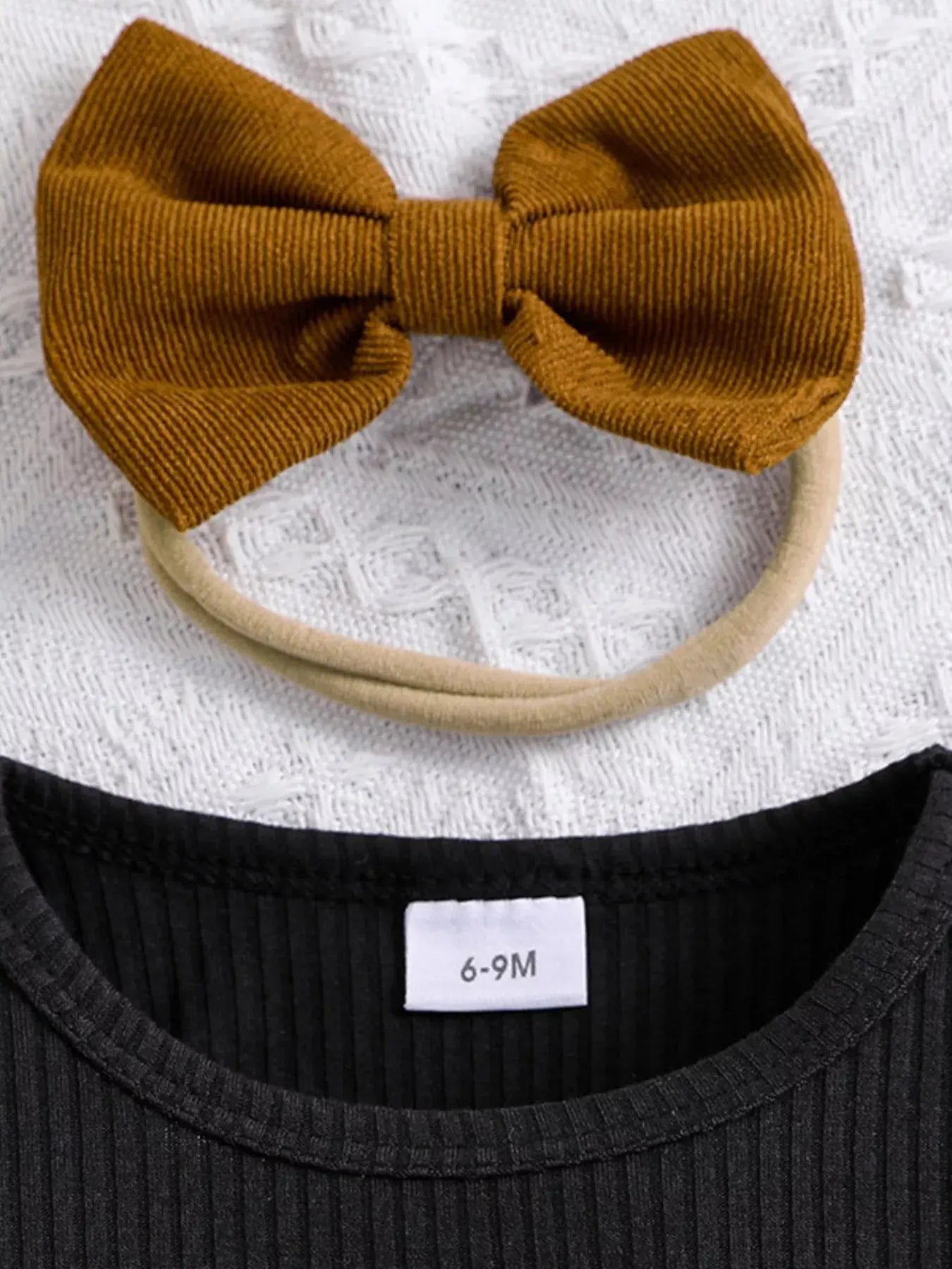 Flat lay of toddler girl ribbed long sleeve top and bow skirt outfit with headband.