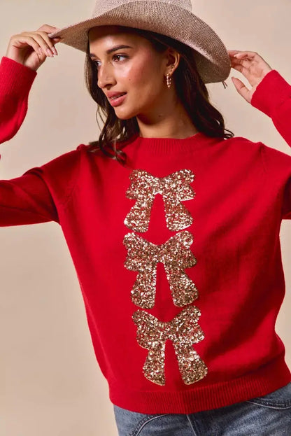 Red Christmas sweater with sequin bow ribbon detail on model with cowgirl hat.
