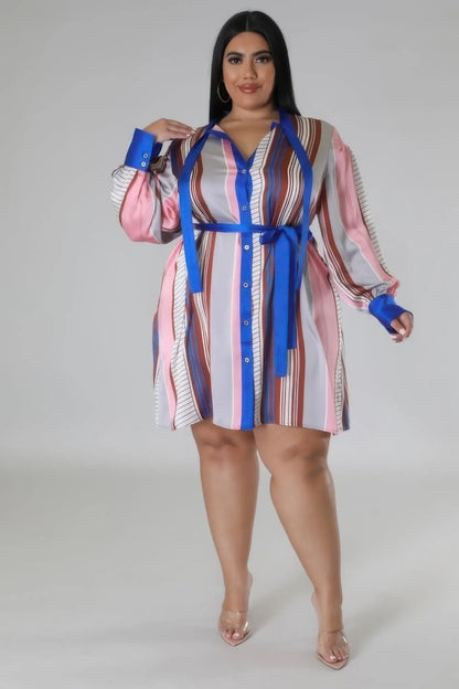 Full body shot of plus size model wearing collared button-down dress with waist tie