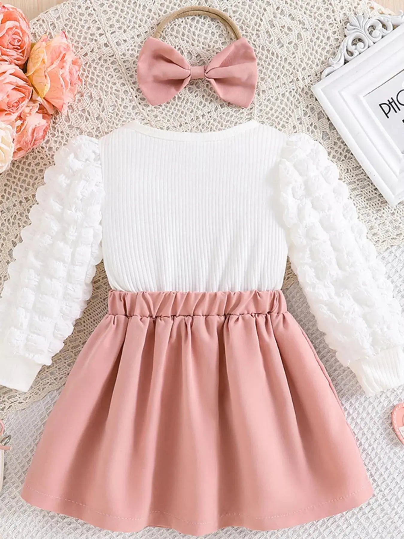 Flat lay of toddler dress and matching headband set in pink and white.