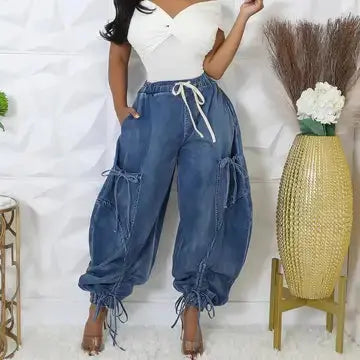 Woman wearing blue cargo pants with a white top in a minimalistic setting.