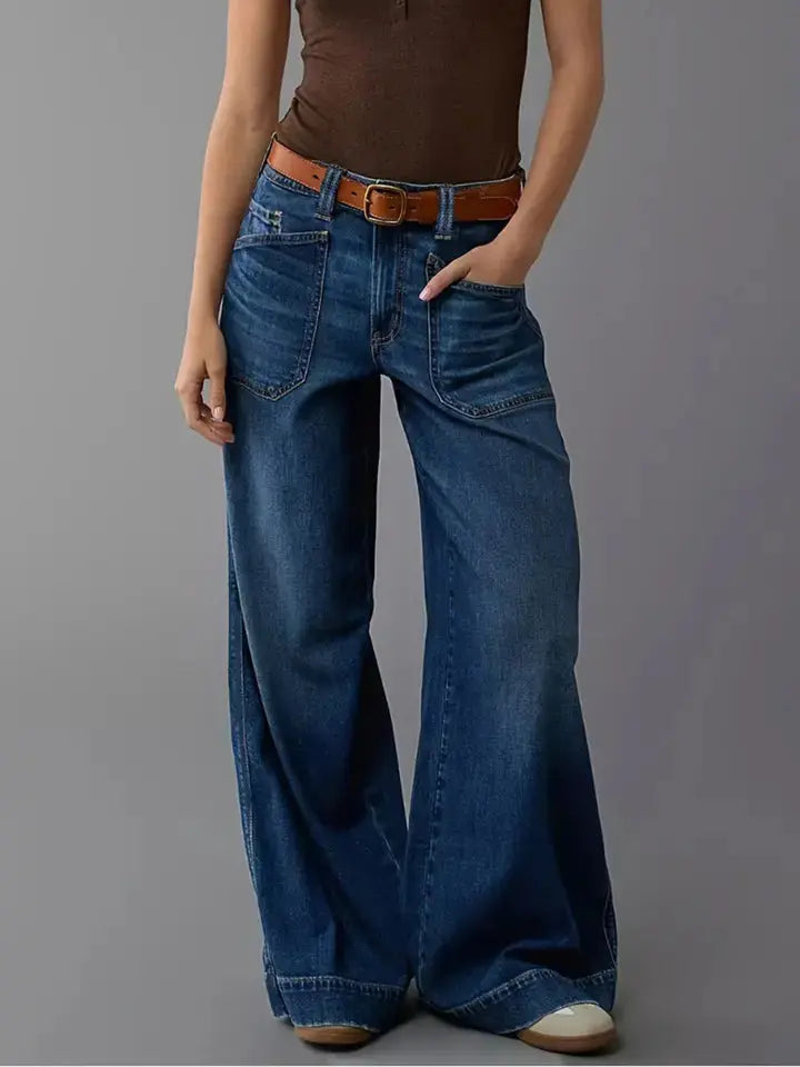 Relaxed fit wide leg denim jeans on model with hands in pockets.