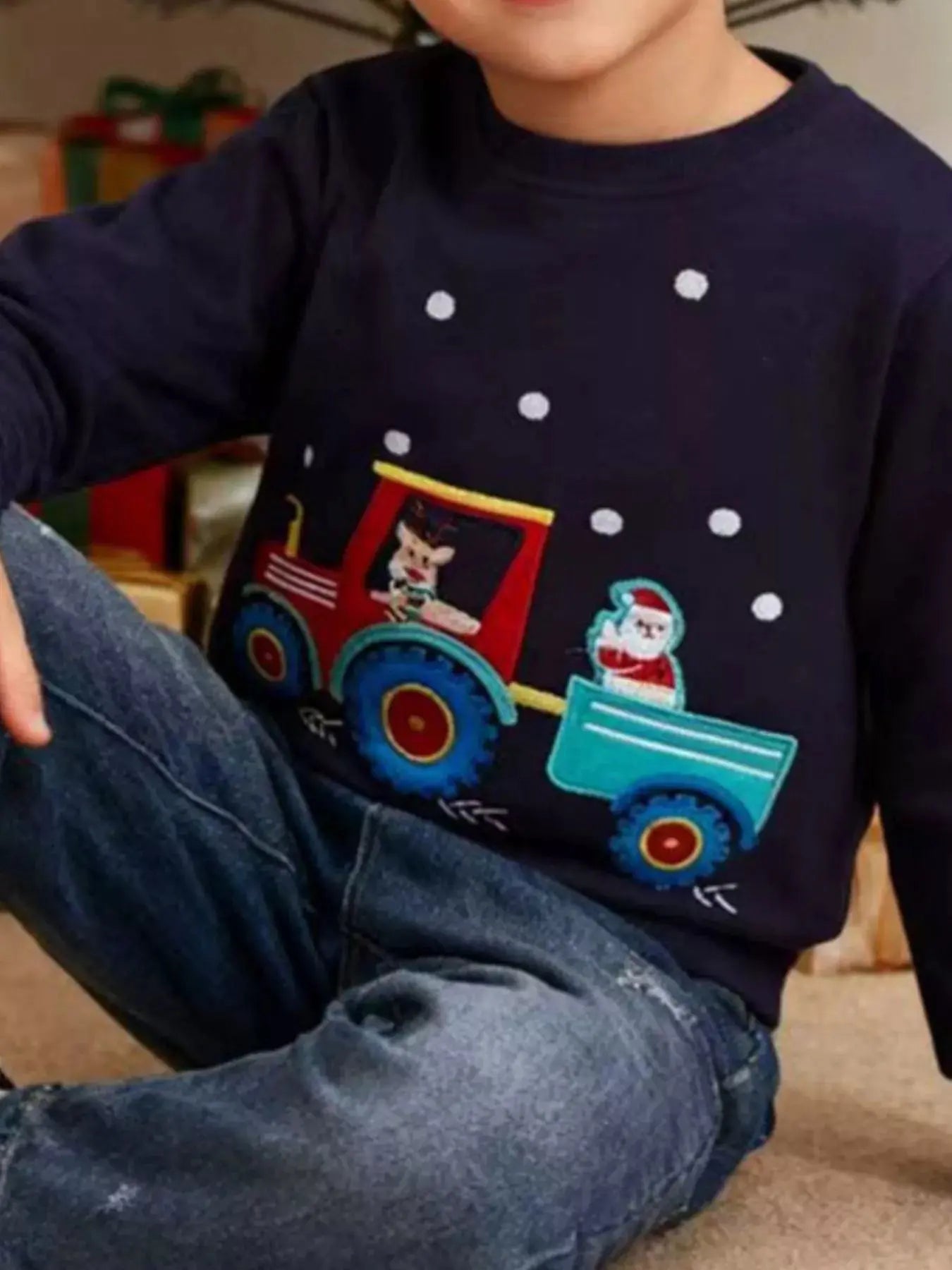Child wearing navy Christmas embroidered sweatshirt with festive design.