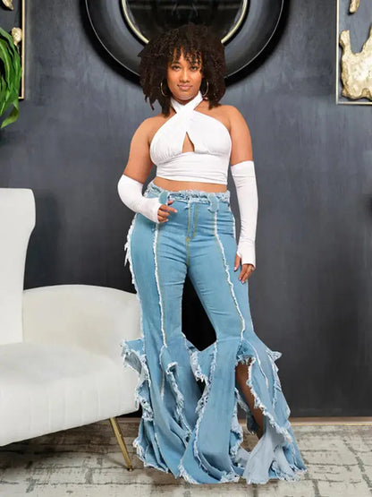 Woman wearing a white halter top and high-waisted, frayed jeans in a room with a gray wall and white chair.