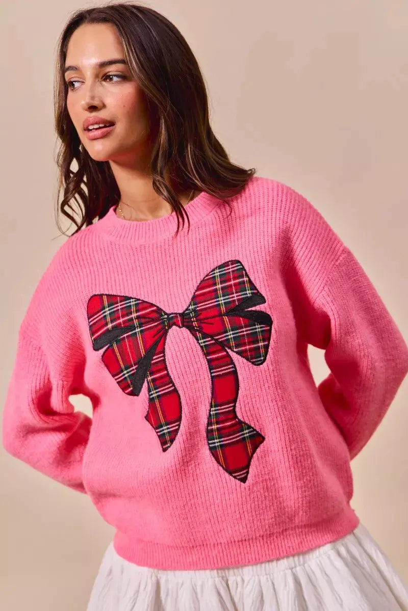 Model wearing pink plaid ribbon holiday sweater.