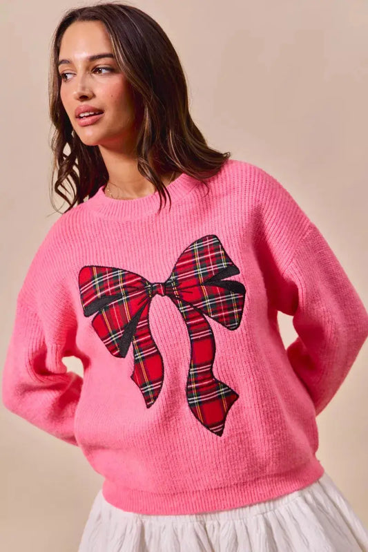 Model wearing pink plaid ribbon holiday sweater.