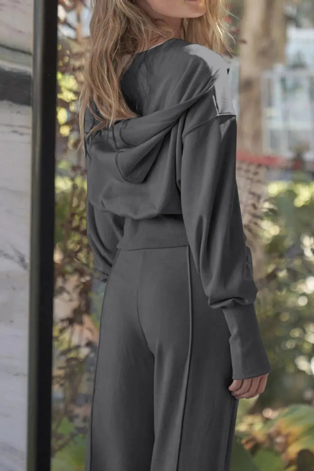 Woman wearing gray zip-up hoodie and wide leg pants active set back view.