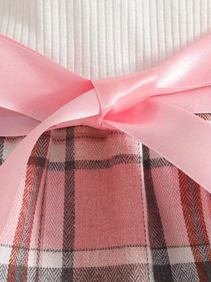 Flat lay of toddler girl plaid skirt outfit with details of front pink bow.