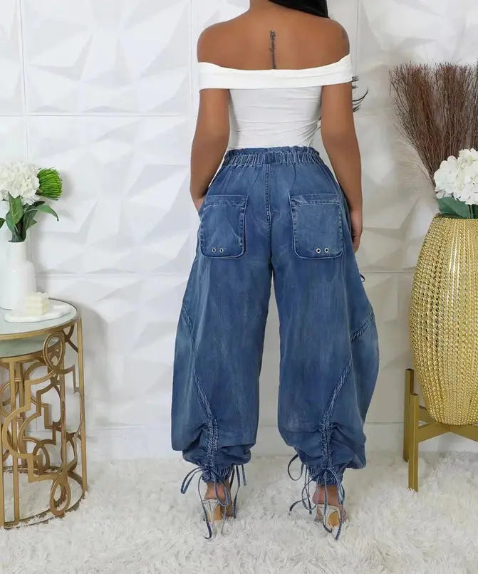 Person wearing blue denim pants and a white top in a minimalistic room with decorative elements back view